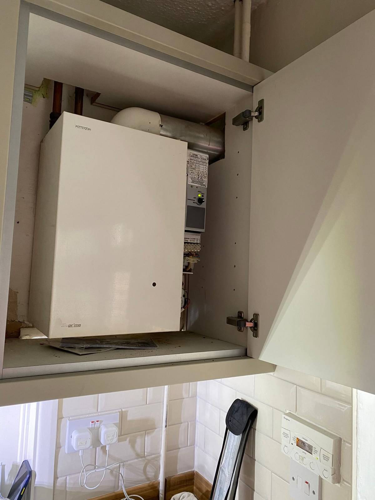 Old Potterton boiler in a kitchen wall cupboard before replacement, Tilehurst